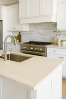 Modern kitchen with white cabinets, beige countertop, and stainless steel appliances.